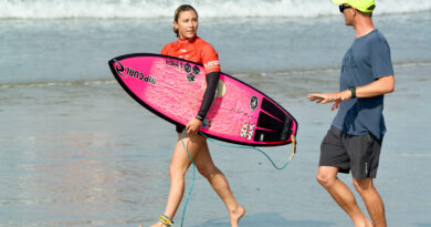 Pro surfer Alyssa Spencer with surfboard running on beach