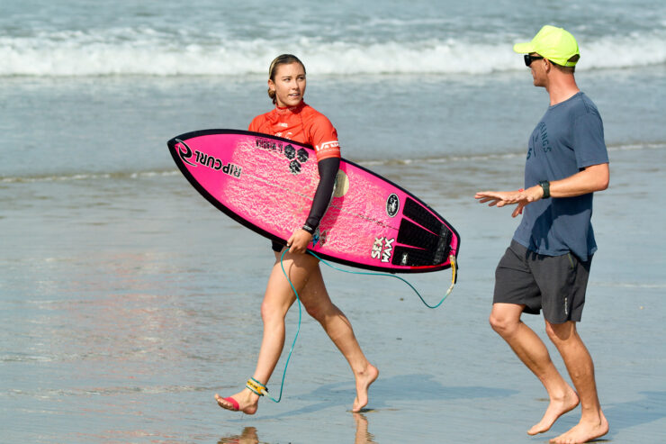 Pro surfer Alyssa Spencer with surfboard running on beach
