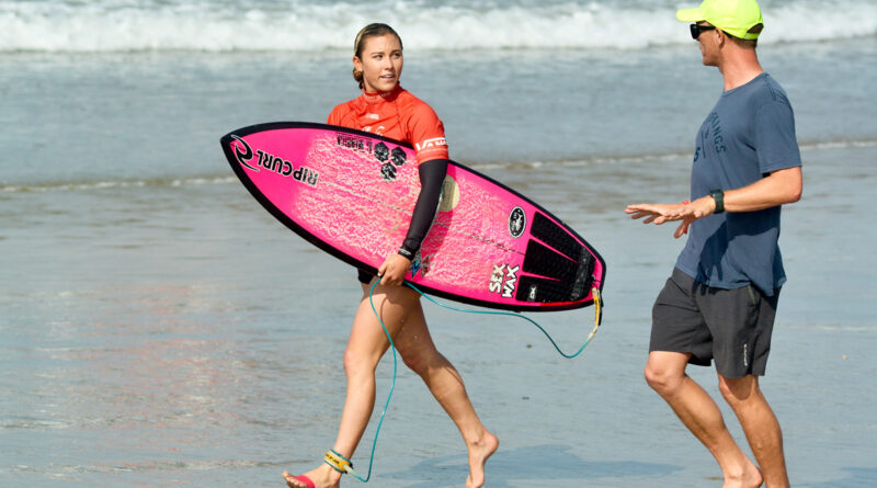 Pro surfer Alyssa Spencer with surfboard running on beach